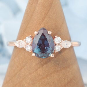 The pear shaped lab alexandrite engagement ring features a large pear alexandrite and two moissanite cluster on two sides, which is a unique alexandrite engagement ring for women.