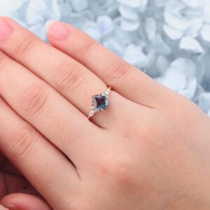 The pear shaped lab alexandrite engagement ring features a large pear alexandrite and two moissanite cluster on two sides, which is a unique alexandrite engagement ring for women.