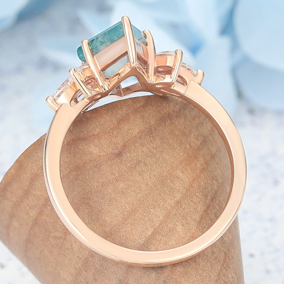 This nature-inspired engagement ring features a striking kite cut moss agate as the center stone, surrounded by a graceful cluster of marquise-cut accents that mimic the look of blooming petals or leaves. The rich, earthy patterns of moss agate make each ring truly one of a kind, while the marquise details add sparkle and movement.